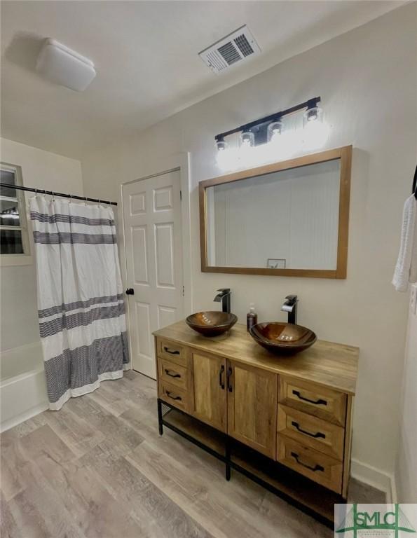 bathroom featuring hardwood / wood-style floors, vanity, and shower / tub combo