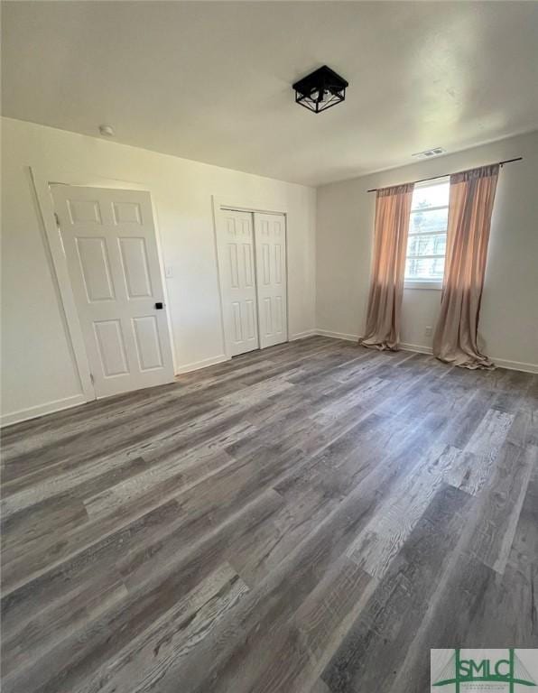 unfurnished bedroom with dark hardwood / wood-style floors and a closet