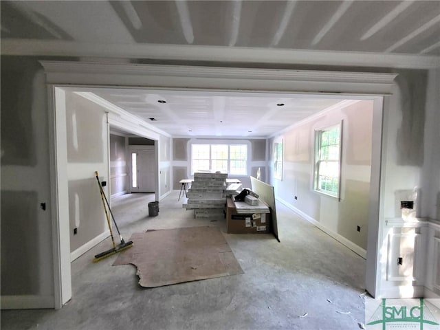 living area with baseboards, ornamental molding, and unfinished concrete floors