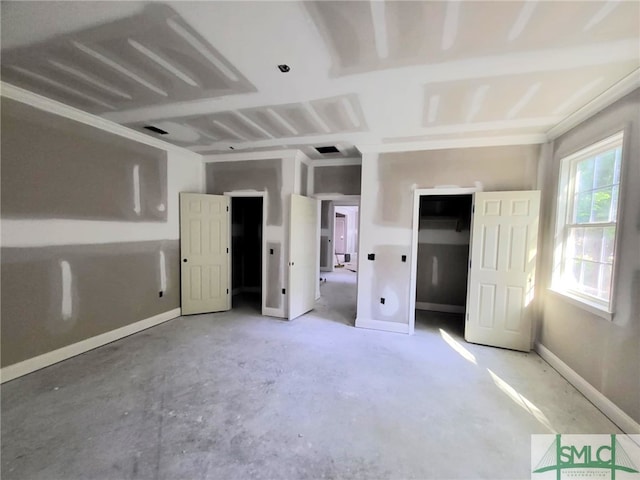 unfurnished bedroom with concrete floors and baseboards