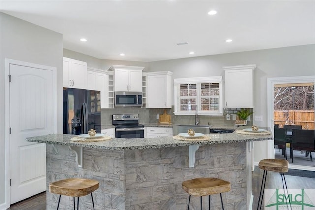 kitchen with sink, light stone countertops, a breakfast bar area, and appliances with stainless steel finishes