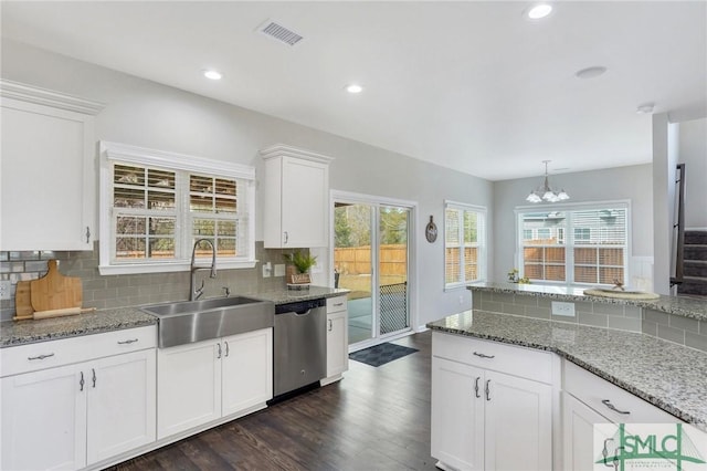 kitchen with an inviting chandelier, white cabinets, sink, stainless steel dishwasher, and tasteful backsplash