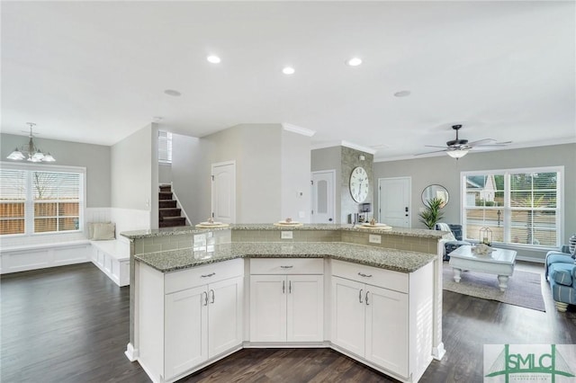 kitchen with ceiling fan with notable chandelier, white cabinetry, hanging light fixtures, and a large island