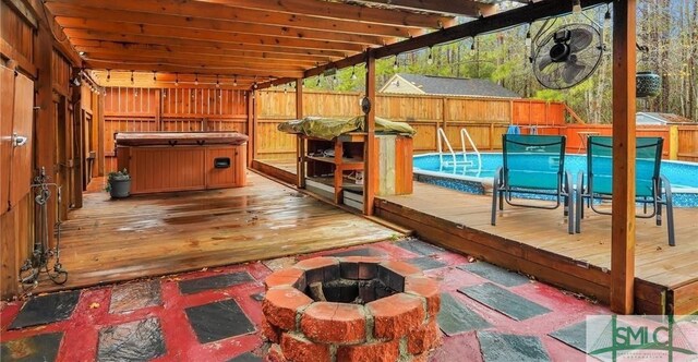 wooden terrace featuring a pool with hot tub and an outdoor fire pit