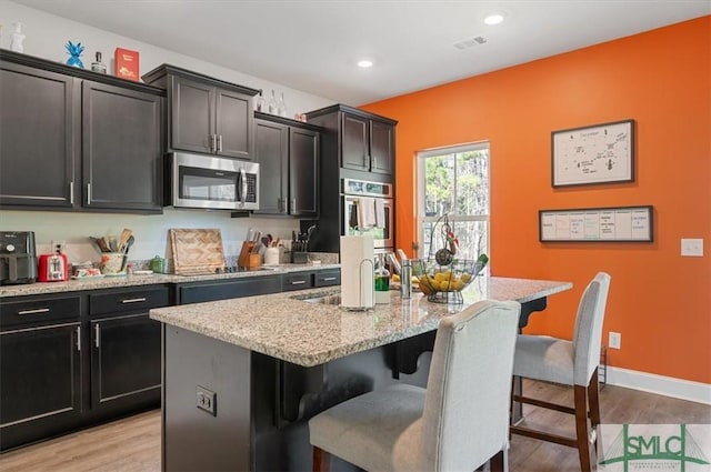 kitchen featuring a breakfast bar area, an island with sink, and light hardwood / wood-style floors