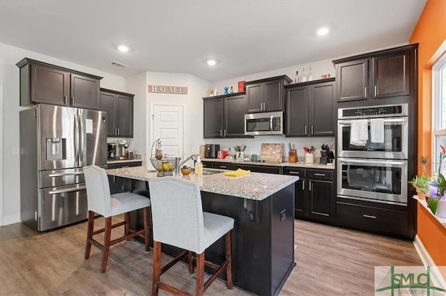 kitchen featuring a kitchen bar, light hardwood / wood-style flooring, an island with sink, and stainless steel appliances