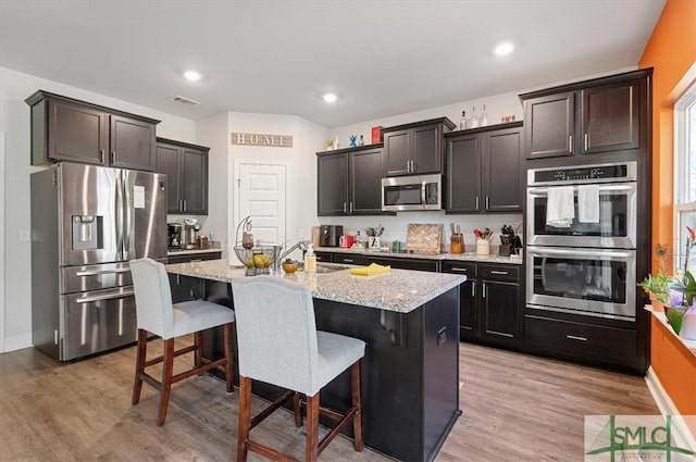 137 William Way, Springfield, GA 31329 - kitchen featuring stainless steel appliances, light stone counters, a kitchen island with sink, a breakfast bar, and light wood-style floors