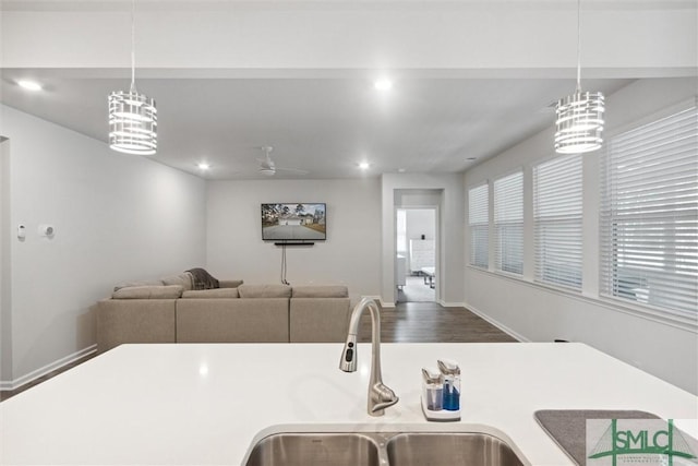 kitchen with wood-type flooring, ceiling fan with notable chandelier, decorative light fixtures, and sink