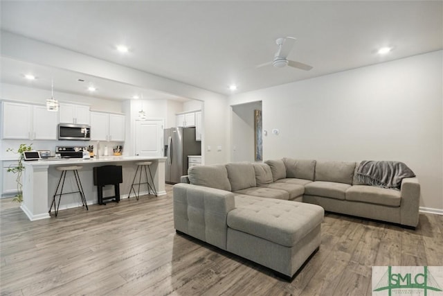 living room featuring light wood-type flooring and ceiling fan