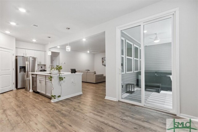 kitchen featuring appliances with stainless steel finishes, ceiling fan, decorative light fixtures, white cabinets, and an island with sink