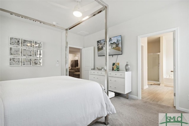 carpeted bedroom with ensuite bath and ceiling fan