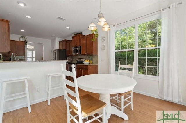 dining area featuring sink, light hardwood / wood-style flooring, and a chandelier