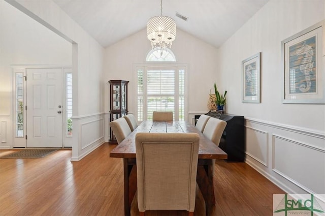 dining area featuring hardwood / wood-style floors, an inviting chandelier, and vaulted ceiling