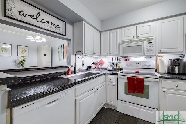 kitchen featuring white appliances, white cabinets, sink, dark tile patterned floors, and a notable chandelier