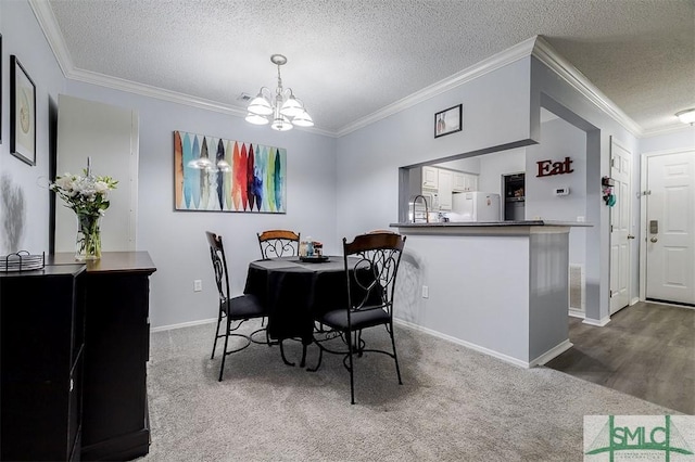 carpeted dining area with ornamental molding, a textured ceiling, and an inviting chandelier