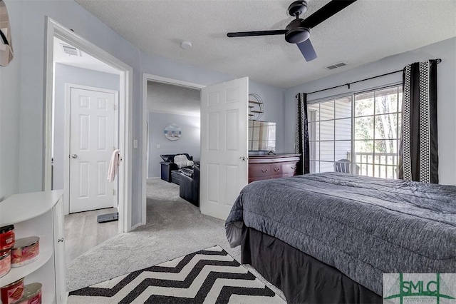 bedroom with ceiling fan, light colored carpet, and a textured ceiling