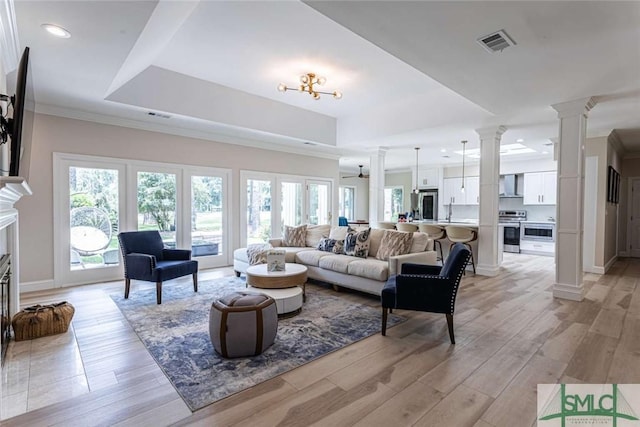 living room with a raised ceiling, ornamental molding, a healthy amount of sunlight, and light hardwood / wood-style floors