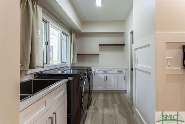 laundry area featuring cabinets, separate washer and dryer, and light hardwood / wood-style flooring