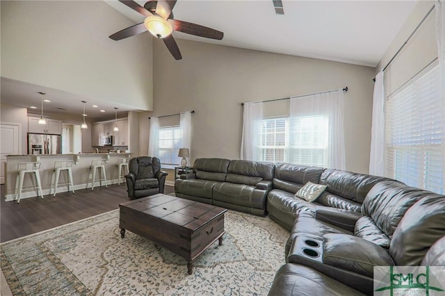 living room with high vaulted ceiling, dark hardwood / wood-style floors, a healthy amount of sunlight, and ceiling fan