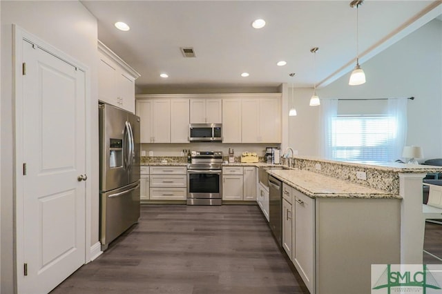 kitchen featuring kitchen peninsula, white cabinets, pendant lighting, and appliances with stainless steel finishes