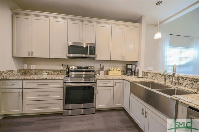 kitchen featuring light stone countertops, sink, dark hardwood / wood-style floors, pendant lighting, and appliances with stainless steel finishes