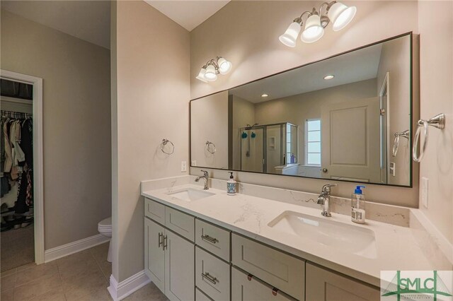 bathroom featuring tile patterned flooring, vanity, toilet, and walk in shower