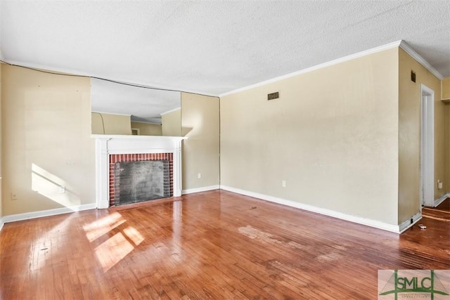 unfurnished living room featuring hardwood / wood-style floors, ornamental molding, a fireplace, and a textured ceiling