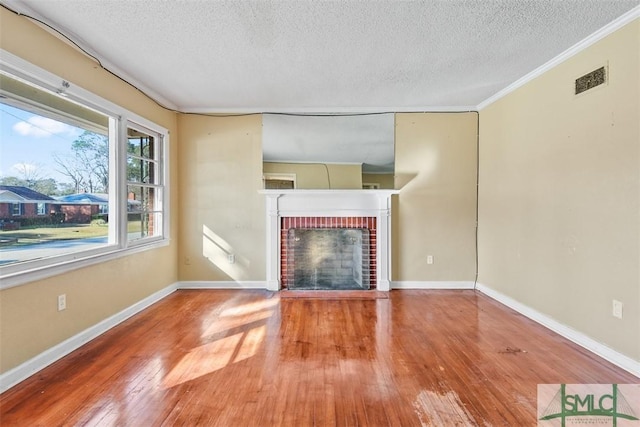 unfurnished living room with a fireplace, hardwood / wood-style floors, a textured ceiling, and ornamental molding