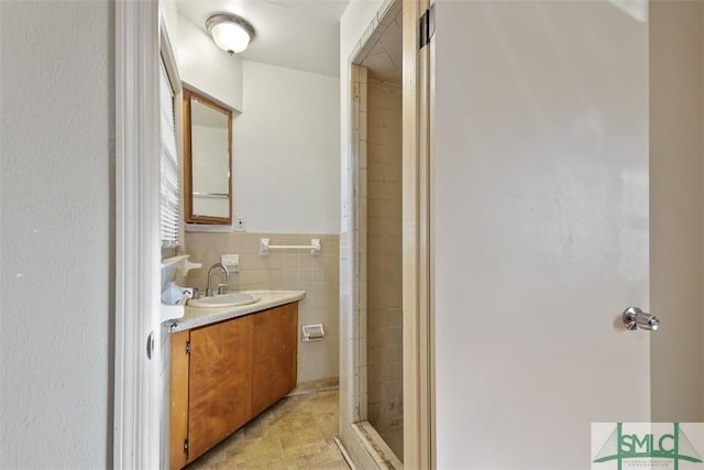 bathroom with an enclosed shower, vanity, and tile walls