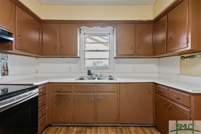 kitchen with stainless steel electric range oven, sink, light hardwood / wood-style floors, and extractor fan