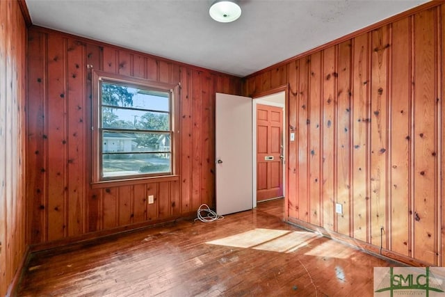 unfurnished room featuring hardwood / wood-style flooring and wood walls