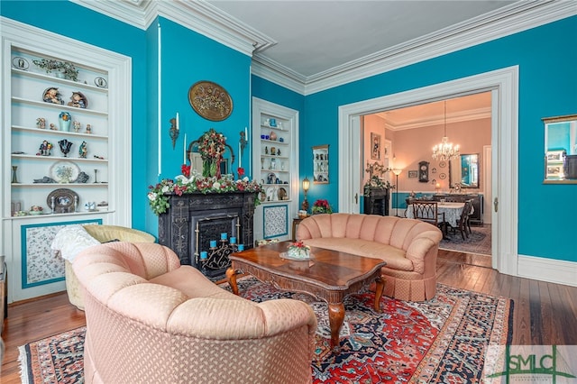 living room with built in shelves, a chandelier, a fireplace, and wood-type flooring