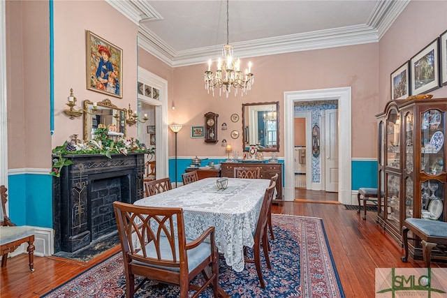 dining area with hardwood / wood-style flooring, an inviting chandelier, and crown molding