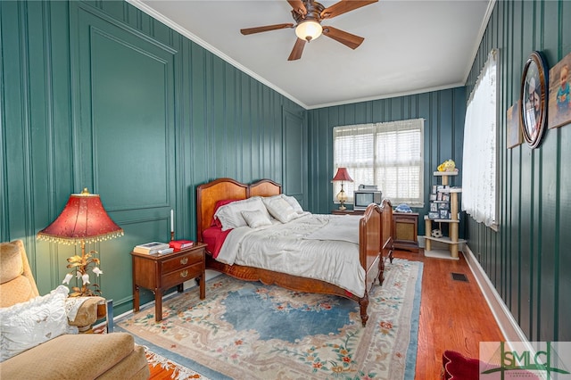 bedroom featuring hardwood / wood-style flooring, ceiling fan, and ornamental molding