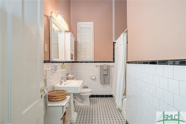 full bathroom with sink, shower / bath combination with curtain, tile walls, and toilet