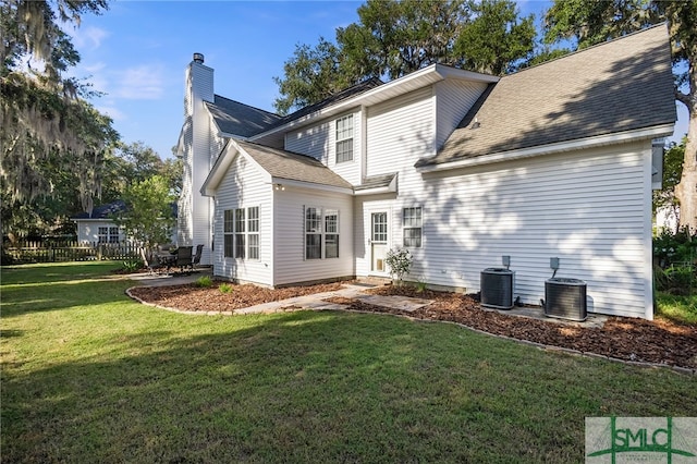 rear view of house with a lawn and central AC