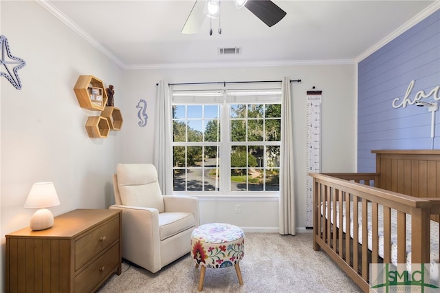 carpeted bedroom featuring a crib, ceiling fan, and ornamental molding