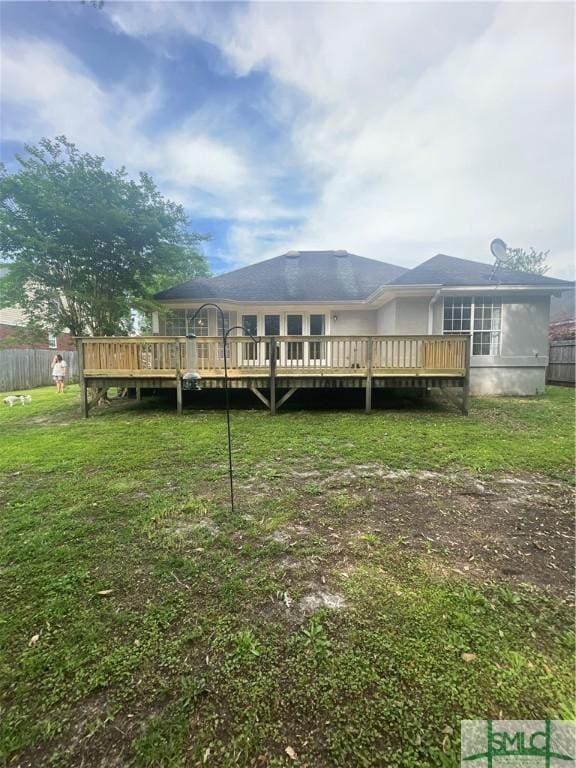 back of property with a lawn and a wooden deck