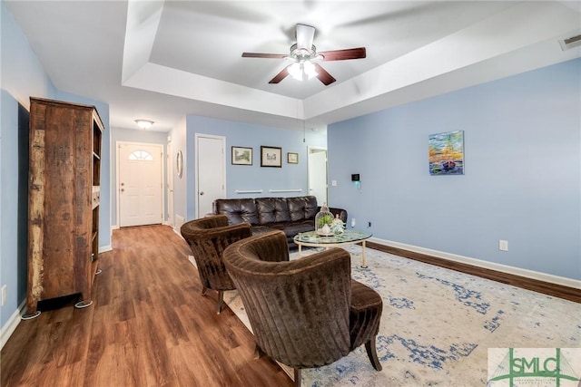 living room featuring a raised ceiling, ceiling fan, and hardwood / wood-style floors