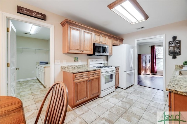 kitchen with white appliances, light stone counters, and light tile patterned flooring