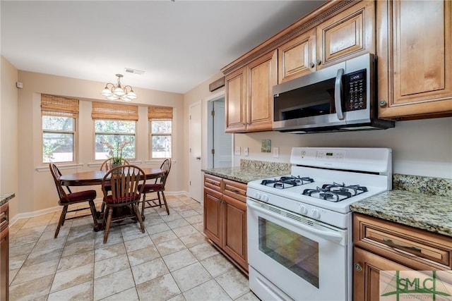 kitchen with light stone countertops, pendant lighting, an inviting chandelier, and gas range gas stove