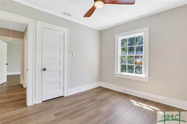 empty room with ceiling fan, light hardwood / wood-style flooring, and crown molding