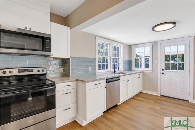 kitchen featuring light stone countertops, sink, decorative backsplash, white cabinets, and appliances with stainless steel finishes