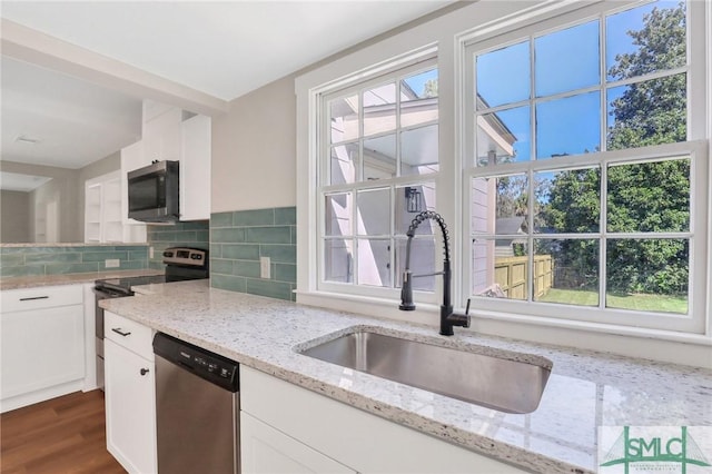 kitchen with light stone countertops, appliances with stainless steel finishes, decorative backsplash, and sink