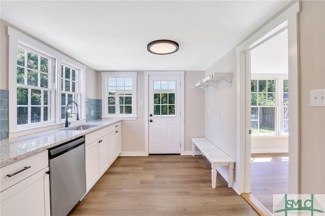 kitchen with dishwasher, sink, light stone countertops, light hardwood / wood-style floors, and white cabinetry