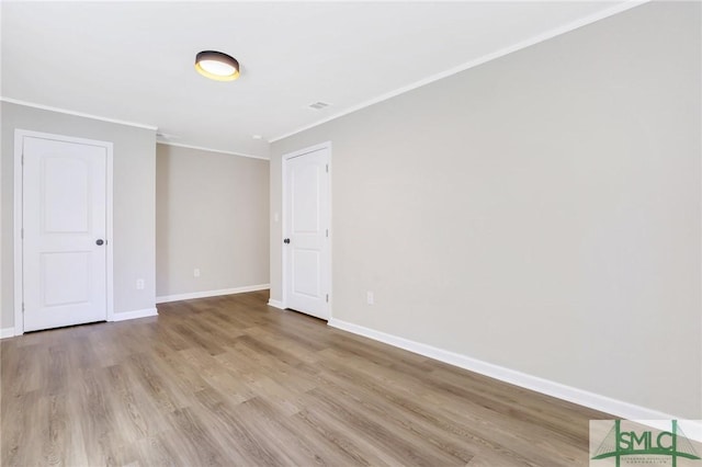 empty room featuring crown molding and light hardwood / wood-style flooring