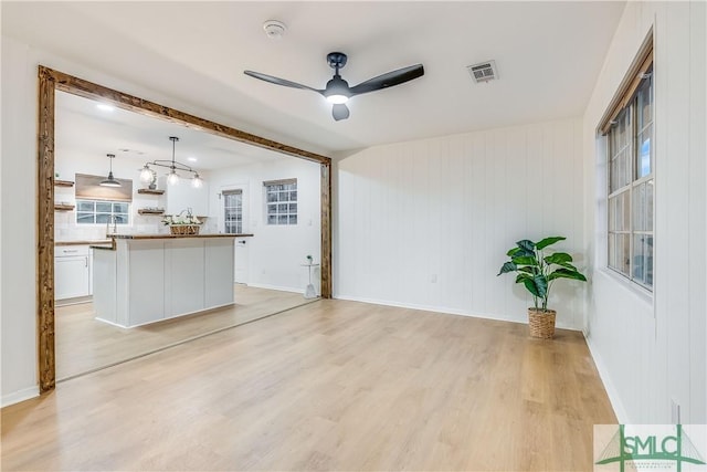 unfurnished living room featuring ceiling fan and light wood-type flooring