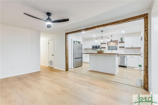 kitchen with a center island, white cabinets, ceiling fan, decorative light fixtures, and stainless steel appliances