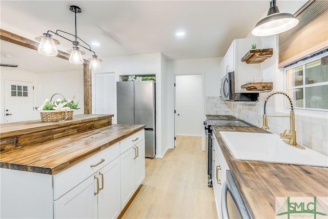 kitchen featuring wooden counters, pendant lighting, and white cabinetry