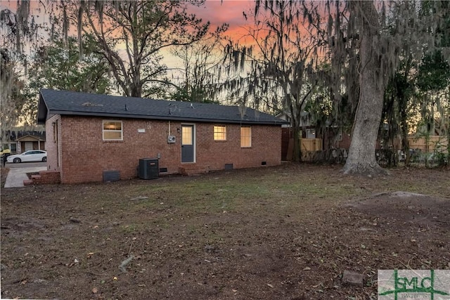 back house at dusk featuring central AC